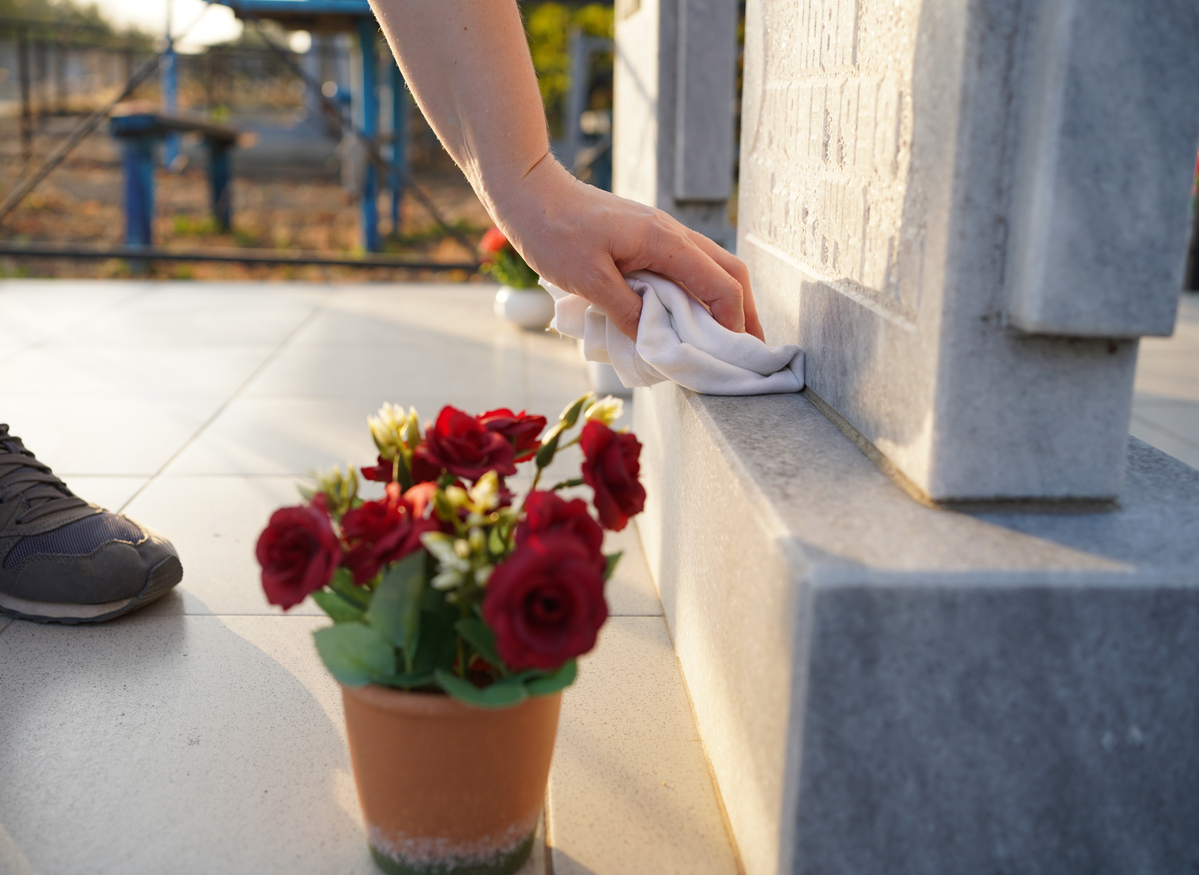 Cleaning the cemetery. A woman's hand washes the grey monument at the grave with a rag. Parents Saturday in Russia. business beautification of the graves.